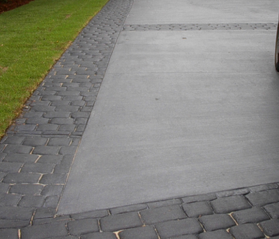 Gray concrete driveway with a gray cobblestone brick design stamped concrete edging.