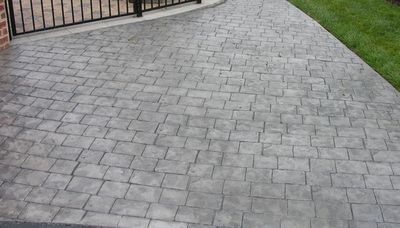 Gray and stamped concrete driveway that resembles an old cobblestone walkway.