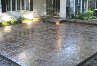 Dark stained and polished stamped concrete patio and step to back door of home.