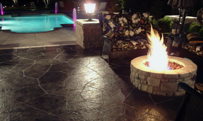 Very dark brown stone style stamped concrete patio with a built in fire pit