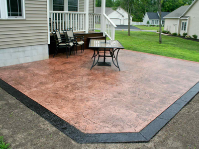 Brown stained stamped concrete patio with a black stained and stamped edge.